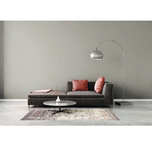 Modernes Wohnzimmer mit grauer Wandfarbe, dunklem Stoffsofa, niedrigem runden Couchtisch, gemustertem Teppich und einer großen Bogenlampe aus Metall.