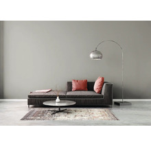 Minimalistisches Wohnzimmer mit dunklem Stoffsofa, rundem Steincouchtisch auf einem Teppich und einer großen gebogenen Stehleuchte aus Metall.