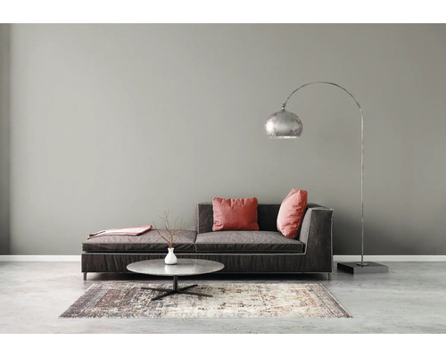 Minimalistisches Wohnzimmer mit dunklem Stoffsofa, rundem Steincouchtisch auf einem Teppich und einer großen gebogenen Stehleuchte aus Metall.
