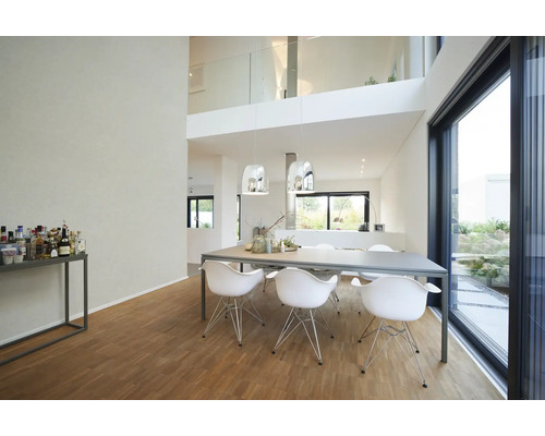 Modernes helles Esszimmer mit großem grauem Tisch, weißen Designerstühlen, Chrom-Pendelleuchten und Holzboden an einer großen Glasfront.