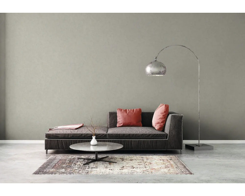 Modernes Wohnzimmer mit strukturierter grauer Wand, dunkelgrauem Sofa, rosa Kissen, Couchtisch und einer großen Bogenlampe aus Metall.