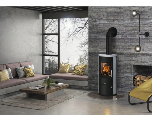Moderner Kaminofen in einem hellen Wohnzimmer im Industrial-Stil mit Sichtbetonwänden und großem Fenster.