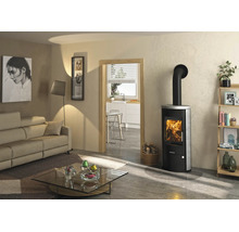 Modernes helles Wohnzimmer mit Justus Kaminofen aus Metall und Stein mit brennendem Feuer, Sofa und Glastisch.