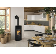 Moderner schwarzer Kaminofen mit sichtbarem Feuer in einer hellen Küche mit Essbereich, weißen Schränken und Holzoberflächen.