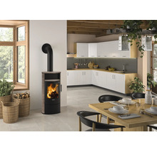 Moderner Kaminofen mit brennendem Feuer in einer hellen Wohnküche mit Küchenschränken, Holztisch und Weidenkörben für Brennholz.