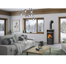 Moderner Kaminofen in hellem Wohnzimmer mit Blick auf verschneite Winterlandschaft durch ein großes Holzfenster.