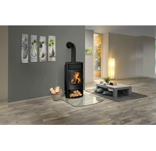 Moderner schwarzer Kaminofen in einem hellen Wohnzimmer mit Holzboden, Glasbodenplatte und Korb mit Brennholz.