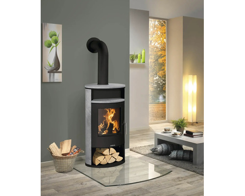 Justus Kaminofen mit Steinverkleidung und brennendem Holzfeuer in einem modern eingerichteten Wohnzimmer auf einer Glasbodenplatte.