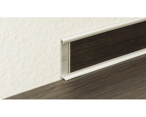 Silbernes Sockelleistenprofil aus Metall mit Einlage in dunkler Holzoptik am Übergang von Wand zu Boden.