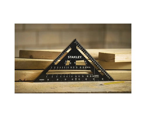Schwarzer Stanley Sparrenwinkel aus Metall mit Messskalen auf hellen Holzbohlen liegend, daneben ein gelber Bleistift in einer hellen Werkstatt.