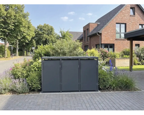 Moderne Dreier-Mülltonnenbox aus Metall in einem gepflegten Vorgarten vor einem Backsteinhaus.