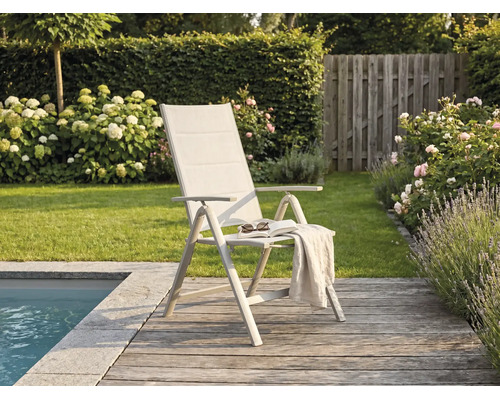 Moderner Gartenklappstuhl mit hoher Rückenlehne auf einer Holzterrasse am Pool, umgeben von einem grünen Garten mit Blumen.