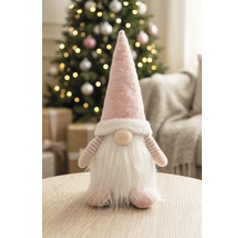 Stoffwichtel mit spitzer Mütze und Bart auf einem Holztisch in einem hellen, festlich dekorierten Raum mit geschmücktem Weihnachtsbaum.