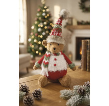Weihnachts-Teddybär aus Plüsch mit Strickmütze und Schal, sitzend auf einem Holztisch in einem hellen, festlich dekorierten Raum.