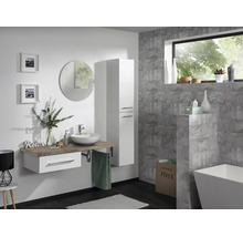 Modernes Badezimmer mit hängendem Waschtisch, weißem Hochschrank, rundem Spiegel und freistehender Badewanne vor grauen Fliesen wirkend.