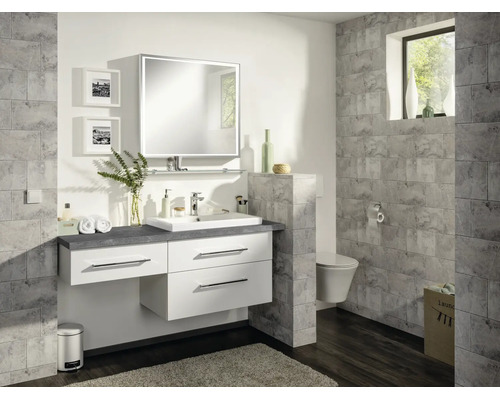 Modernes Badezimmer mit weißem Waschtischunterschrank, beleuchtetem Spiegel und grauen Wandfliesen in Steinoptik.