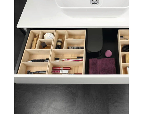 Organisierte Bad-Waschtischschublade mit Schubladeneinsätzen aus Holz, gefüllt mit Pflegeutensilien, Bürsten und einem Handtuch unter einem Waschbecken.