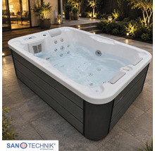 Rechteckiger Außenwhirlpool mit Massagedüsen, Kopfstützen und Holzoptik-Verkleidung auf einer beleuchteten Terrasse. Sanotechnik International Logo.