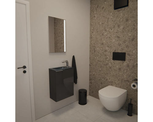 Moderne Gäste-Toilette mit wandhängender Toilette, Hängewaschbecken, Spiegel und Badaccessoires vor einer Wand in Steinoptik.