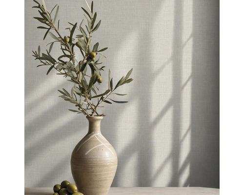 Tapete in Leinenoptik an einer Wand mit einer Keramikvase und einem Olivenzweig im hellen Sonnenlicht.