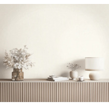 Modernes Sideboard mit geriffelter Front, dekoriert mit Glasvase mit Trockenblumen, Tischlampe und Keramikobjekten vor einer hellen Wand.