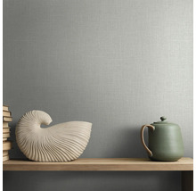 Vliestapete mit Textilstruktur in Leinenoptik an einer Wand hinter einem Holzregal mit Muschelskulptur und Teekanne.