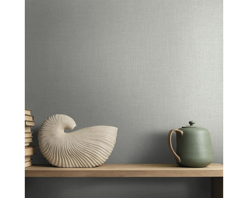 Vliestapete mit Textilstruktur in Leinenoptik an einer Wand hinter einem Holzregal mit Muschelskulptur und Teekanne.