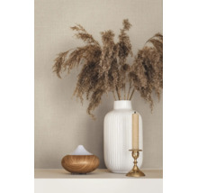 Strukturierte beige Tapete in Leinenoptik hinter einer weißen geriffelten Vase mit Trockengras, einem Aroma-Diffuser und einem Kerzenständer.