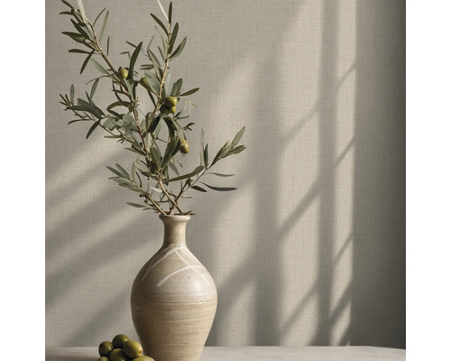 Vliestapete mit Leinenstruktur an einer Wand hinter einer Vase mit Olivenzweig und Schattenwurf.