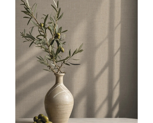 Tapete mit feiner Leinenstruktur hinter einer Keramikvase mit Olivenzweigen in einem hellen Raum mit Schattenwurf.
