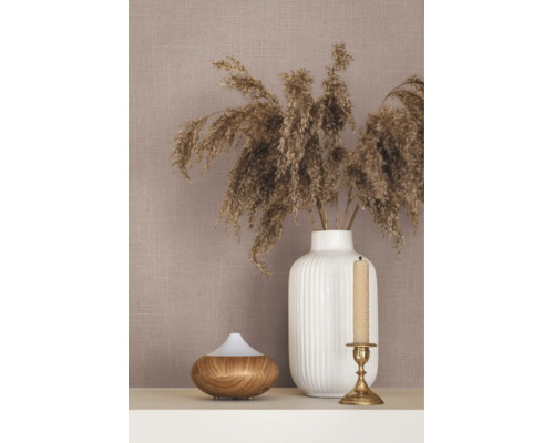 Tapete mit Leinenstruktur, dekoriert mit einer weißen geriffelten Vase mit Trockengras, einem Aroma Diffuser in Holzoptik und einem Kerzenständer.