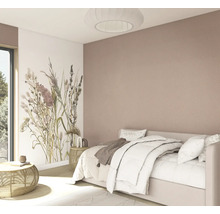 Helles Schlafzimmer mit weißem Bett, floraler Fototapete und altrosafarbener Wand, Beistelltischen aus Rattan sowie einer runden Plissee-Leuchte.