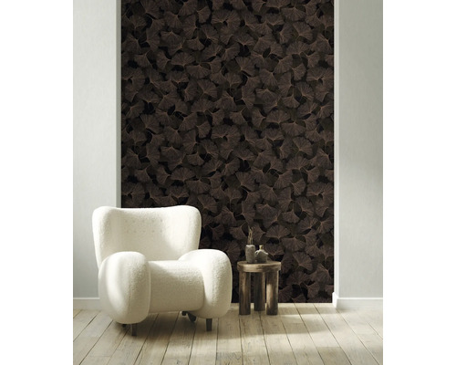 Vliestapete mit Ginkgo-Blatt-Muster in einem hellen Wohnzimmer mit weißem Sessel und Holztisch.