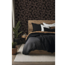 Ein Schlafzimmer mit dunkler Tapete mit Ginkgoblatt-Muster, einem Holzbett mit grauer Bettwäsche, Zimmerpflanzen und einem hellen Teppich.