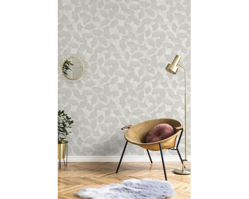 Vliestapete mit Ginkgoblatt-Muster in einem hellen Wohnraum mit Sessel, Stehlampe und Parkettboden.