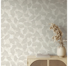 Tapete mit Ginkgo-Blattmuster in hellem Wohnraum hinter einem Sideboard aus Holz mit Vase und Trockenblumen.