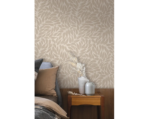 Tapete mit Blattmuster im Schlafzimmer über einem Nachtkästchen mit Vasen und Trockenblumen neben einem Bett.