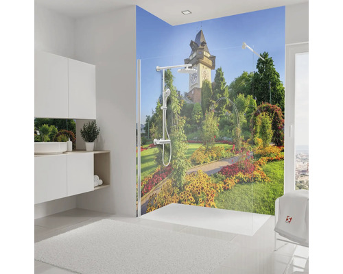 Duschrückwand mit Motiv des Grazer Uhrturms und Garten in einem hellen, modernen Badezimmer mit Glasduschwand.