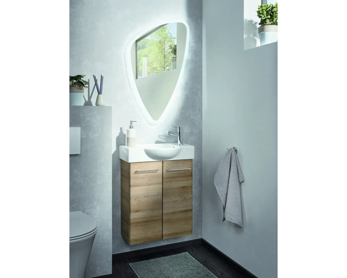 Modernes helles Gästebad-Set mit wandhängendem Waschbeckenunterschrank in Holzoptik, Keramikwaschbecken und asymmetrischem Spiegel mit Beleuchtung.