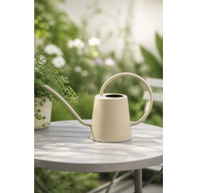 Beige Gießkanne aus Metall mit langem Ausguss und rundem Griff auf einem Gartentisch.