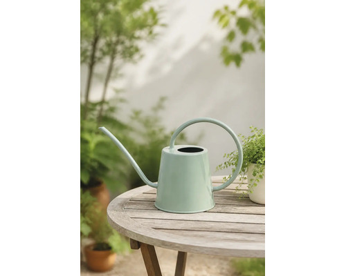Moderne mintgrüne Metallgießkanne mit langem Ausguss und großem Rundgriff auf einem hölzernen Gartentisch.