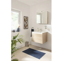 Modernes, helles Bad mit wandhängendem Waschtisch in heller Holzoptik, weißem Waschbecken, Spiegelschrank, Armatur und blauem Badeteppich.