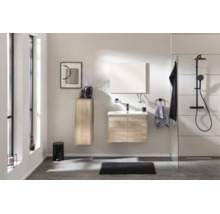 Modernes Badezimmer-Set in Eiche-Optik mit Waschbeckenunterschrank, Spiegel, Hochschrank und schwarzem Duschsystem in hellem, offenem Raum.