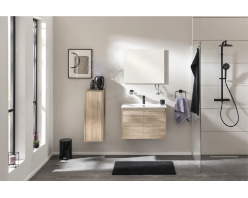 Modernes Badezimmer-Set in Eiche-Optik mit Waschbeckenunterschrank, Spiegel, Hochschrank und schwarzem Duschsystem in hellem, offenem Raum.