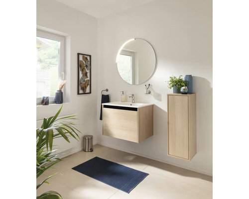 Helles Badezimmer mit wandhängendem Waschtischunterschrank und Seitenschrank in Eichenoptik, weißem Waschbecken und rundem Spiegel.