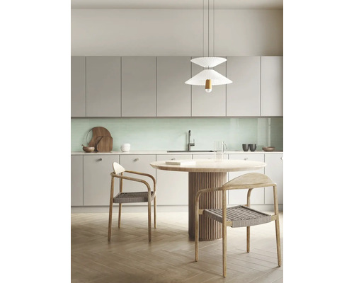 Moderne Küche mit hellgrauen Schränken, mintgrünem Fliesenspiegel, rundem Holztisch und Flechtstühlen unter einer weißen Pendelleuchte.