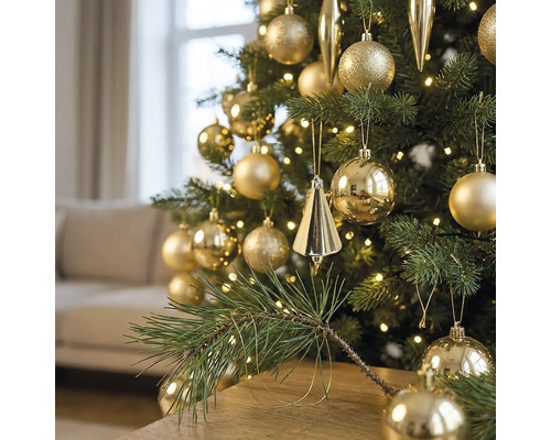 Weihnachtsbaum dekoriert mit goldenen Kugeln und Zapfen, beleuchtet mit warmweißen LED-Lichterketten in einem Wohnzimmer.
