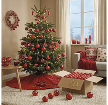 Festlich geschmückter Weihnachtsbaum mit roten Kugeln und LED-Lichterkette in einem wohnlichen Zimmer mit Sofa und Weihnachtsdekoration.