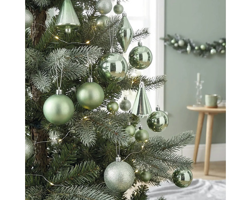 Christbaum dekoriert mit matten, glänzenden und glitzernden Kugeln, tropfenförmigen Ornamenten und einer LED-Lichterkette in hellem Ambiente.