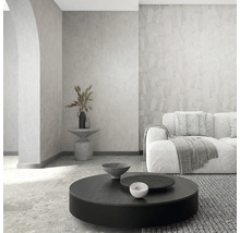 Modernes Wohnzimmer mit gemusterter Vliestapete, strukturierter Wand, Sofa und rundem Couchtisch in hellem, minimalistischem Design.